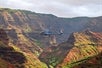 A helicopter flying by a red-colored mountain range on the Kauai Eco Adventure Helicopter Tour in Hawaii USA.
