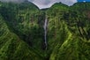 A waterfall flowing down a vegetation covered cliffside on the Kauai Eco Adventure Helicopter Tour in Hawaii USA.
