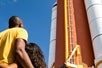 Dad and daughter look up at a space shuttle