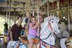 A mother and her young daughter riding a carousel together and laughing at Kings Dominion in Doswell, Virginia.