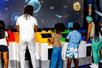 A line of parents and children playing a space game on a large screen in front of them at LEGO Discovery Center Boston.