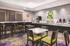 A dining room with a several tables and chairs and a full breakfast bar on the cabinets along the wall at the La Quinta by Wyndham in New Braunfels, Texas.