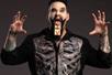 John Shaw in a suit with a skeleton on it performing a trick his a mouse trap on his tongue at the Late Night Magic Las Vegas.
