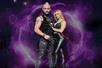 A man and woman in black leather outfits posing together with a smoky purple and black background.