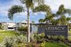 The sign for Legacy Vacation Resorts with a small palm tree next to it and the resort in the background.