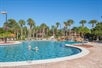 A outdoor pool with bright blue water, sun loungers and trees in the landscaping.