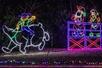 The North Pole rodeo light display with a man riding a polar bear and two people watching on the Lights of Joy Christmas Drive-Thru.