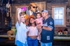 A family taking a selfie with a dog animatronic playing a guitar at Lonely Dog Immersive Experience.