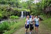 Three adults and a child posing for a photo with a waterfall and other tourists in the background.