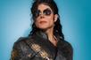 Michael Knight dressed in a Michael Jackson costume including sunglasses and a wig with a light blue background behind him.