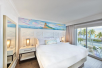A modern-style guest room with a king bed, private balcony, and a view of the ocean at Margaritaville Beach House Key West, FL.