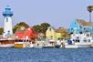 The Marina del Rey harbor full of ships with colorful houses behind them on a sunny day in California.