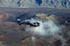 A Maverick airbus flying over the Haleakala Crater with steam rising up from the rocky ground on a sunny day on Maui.