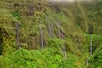 Several thin waterfalls flowing down a cliffside in small groups on the Maui Spectacular Helicopter Tour in Hawaii USA.