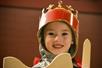 A child is dressed up  with a crown, sword, and shield
