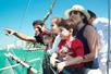 A mother and father with three kids leaning on the railing of a pirate ship and looking at the sights on the tour on a sunny day in Miami.