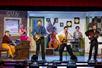 The cast of the Million Dollar Quartet on a 50s themed stage singing and playing various instruments.