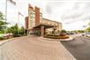 The front entrance to the Monte Carlo Inn - Vaughan Suites with a round driveway with a fountain and flowers in the middle.