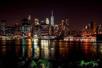 View of New York City at night with the city lights reflecting on the water on the NYC Skyline Sunset Cruise.