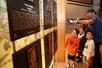 A father and his sons looking at plaques on the wall in front of them in the Hall of Fame at Citi Field Baseball Park.