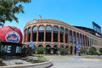 The exterior of Citi Field Baseball Park with the bright red Mets apple to the left on a sunny day in New York City.