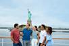 A group of friends chatting on the deck of a cruise boat with the Statue of Liberty in the background on the New York Signature Lunch Cruise.