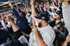 A crowd of Yankees fans screaming and cheering with their fits in the air at a Yankees game in NYC, New York.