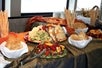 A table full of several type of crackers, cheeses, fruits, and other snacks on the Newport Beach Sights & Sips Cruise by Hornblower.