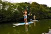 Two guest on the Anahulu River, cheerfully doing the stand up paddleboarding.