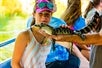 A girl smiling with an alligator hatchling in front of her at Cajun Pride Swamp Tours in New Orleans, Louisiana.