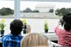 Several people taking photos out of the window of a cruise boat as they sail by a historical monument on the Odyssey Washington DC Premier Lunch Cruise.