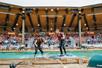 Two lumberjacks standing on a rolling long in water with a crowd of people behind them at Paula Deen's Lumberjack Feud Supper Show.
