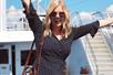A blonde woman in a black dress and sunglasses with her arms out smiling on a bright sunny day on the Spirit of Philadelphia Signature Lunch Cruise.