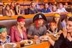 A family dressed as pirates enjoying their dinner in the stands at Pirates Dinner Adventure Orlando with other guests around them.