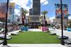 The outdoor pool and lounge area with a grassy area dedicated to corn hole and lounge chairs to the left and right on a sunny day at the Planet Hollywood Resort.
