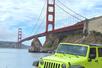 A parked neon green Jeep with the Golden Gate Bridge behind it on a sunny day in San Francisco, California.