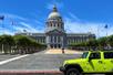A neon green jeep parked in front of San Francisco City Hall with rows of trees leading to the building on both sides on a sunny day.