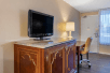 A flat screen TV, desk and chair, and a lamp inside a guest room at Quality Inn Kennedy Space Center, Florida.