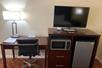 A work area with a desk, flat-screen TV, mini-fridge, microwave inside a guest room at Quality Inn Ukiah Downtown, CA.