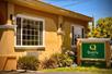 A small green and beige sign for the Quality Inn Ukiah Downtown next to a small landscaped area on a sunny day.