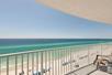 View of the ocean from a private balcony with white railing and a lounge chair on a sunny day in Panama City Beach.