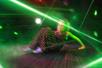 A young girl in climbing over and under green laser at Ripleys Super Fun Park.