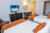Guest room with 2 queen beds and flat-screen TV at Riviera Suites, FL.