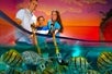 A smiling family—two adults and a child—interacting with colorful fish in a shallow aquarium, set against a vibrant sunset backdrop.