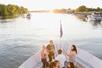 People gathered at the front of the boat chatting with drinks in hand at sunset on the Sacramento River: Alive After Five Cruise.