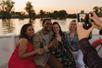A group of friends posing for a photo with the sunsetting in the background on the Sacramento River: Alive After Five Cruise.