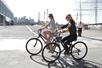 Two women riding bikes down the street on a sunny day while laughing with each other in Santa Monica.