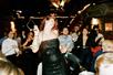 A woman in a black sequin dress dancing with her head thrown back as the guests around her watch.