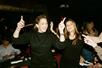 Two women in black dresses standing up and dancing as the Dueling Pianos' duo play guests song requests.