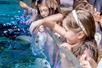 A group of young girls sticking their hands in a touch pool to interact with the sting rays that are bobbing up.
